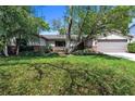 Inviting single-story home with a lush green lawn, mature trees, and a well-manicured landscape at 568 Gainsboro St, Deltona, FL 32725