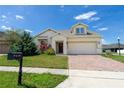Charming home with a two-car garage and a brick paved driveway, complimented by a green lawn and mature landscaping at 1720 Reflection Ln, St Cloud, FL 34771