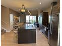 Open-concept kitchen with island seating, stainless appliances, and access to outdoor patio at 3060 Rockefeller Way # 156, Kissimmee, FL 34747