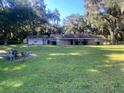 Exterior photo of a ranch-style house with an attached building on a large, grassy lot at 3 Lakeside Dr, Ocala, FL 34482
