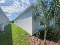 Side view of a home with a well-maintained lawn and mulch, and gray exterior at 4910 Lyric Dr, Mascotte, FL 34753