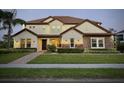 Charming two-story home featuring a well-maintained lawn, stone accents, and warm exterior lighting at dusk at 7443 Lake Albert Dr, Windermere, FL 34786