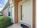 Inviting entryway with a white front door, sidelight window, and decorative landscaping at 9582 Sw 70Th Loop, Ocala, FL 34481