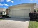 Home exterior featuring a two-car garage with a sliding screen door, and well-maintained landscaping at 9582 Sw 70Th Loop, Ocala, FL 34481
