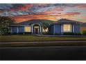 Charming blue home with picturesque sunset backdrop, beautiful landscaping, and well-lit windows at 5810 Lake Victoria Dr, Lakeland, FL 33813