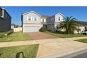 Two-story home with brick driveway, two-car garage, manicured lawn, and a mature palm tree at 1142 Blarney St, Minneola, FL 34715