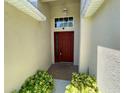 Close-up shot of a welcoming front entryway with a red door and neatly trimmed green bushes at 1003 Clearpointe Way, Lakeland, FL 33813