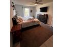 Comfortable bedroom featuring a ceiling fan, TV, dresser and a window with natural light at 6762 Pomeroy Cir, Orlando, FL 32810