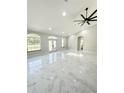 Bright living room featuring marble floors, modern ceiling fan, and three big windows at 13619 Sw 78Th Pl, Dunnellon, FL 34432