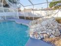 Screened-in pool featuring a rock waterfall feature for ultimate relaxation and enjoyment at 3955 Sw 139Th Street Rd, Ocala, FL 34473