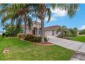 Attractive single-story home with palm trees, red brick-lined flowerbeds, and a spacious driveway leading to a two-car garage at 508 Bacio St, New Smyrna Beach, FL 32168