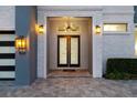 Elegant entryway featuring a double door, custom lighting, and decorative brick accents at 1514 Corolla Ct, Reunion, FL 34747
