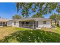 Spacious backyard featuring a screened-in lanai, lush green grass, and a private outdoor space for relaxation and entertainment at 2382 Due West Dr, The Villages, FL 32162
