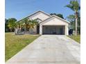 Exterior of home with attached garage, concrete driveway, and lawn at 323 Miami Ln, Kissimmee, FL 34759