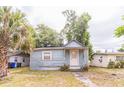 Exterior of home with light blue siding, white trim, small front porch and overgrown yard at 515 New York Ave, St Cloud, FL 34769