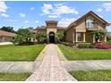 Charming home with red tile roof, arched entry, second story balcony, lush landscaping, and brick paver walkway at 6567 Eagle Ridge Way, Lakeland, FL 33813