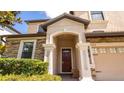 Inviting front porch with stone accents, stately columns, and a beautiful wood front door at 1450 Rolling Fairway Dr, Davenport, FL 33896