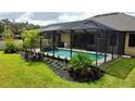 Screened-in lanai featuring a refreshing pool with tropical landscaping and a waterfall feature at 1568 Cordgrass Way, Lakeland, FL 33813