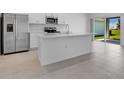 Bright kitchen featuring stainless steel appliances, an island with a sink, and sliding glass doors leading to outdoor space at 5133 Forget Me Not Ave, Lake Hamilton, FL 33851