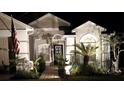 Exterior view of a well-lit home at night, showcasing landscape lighting and manicured greenery at 3905 Westerham Dr, Clermont, FL 34711