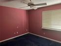 Bedroom with maroon walls, uncarpeted floors, a window, and a ceiling fan at 116 Wild Holly Ln, Longwood, FL 32779