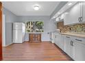 Bright kitchen featuring white cabinets, a mosaic backsplash, and a window overlooking a tree filled yard at 641 Jackson St, Eustis, FL 32726