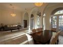 Open-concept living room and dining area with tile floors, large arched windows, and elegant chandeliers at 1695 Horseshoe Rd, Deltona, FL 32725