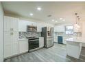 Modern kitchen with stainless steel appliances, white cabinetry, a stylish backsplash, and sleek gray flooring at 7331 Blue Jacket W Pl, Winter Park, FL 32792