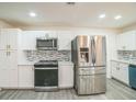 Bright kitchen featuring stainless steel appliances, white cabinets, updated backsplash, and ample counter space at 7331 Blue Jacket W Pl, Winter Park, FL 32792