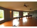 Spacious living room offering a pool table, ceiling fans, and natural light at 10411 County Road 474, Clermont, FL 34714