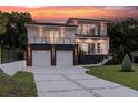 Modern two-story home featuring a two-car garage and a landscaped front yard, complemented by ambient outdoor lighting at 1841 Moorings Ct, Clermont, FL 34711
