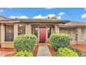 Charming single Gathering home with a well-manicured lawn, beautiful landscaping, and a red front door at 4120 Chelsea Ln, Lakeland, FL 33809