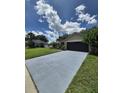 View of single-story home with black garage door and blue driveway on a sunny day at 15917 Mercott Ct, Clermont, FL 34714