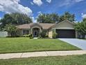 Charming single-story home with a well-manicured lawn, black garage door and a blue driveway at 15917 Mercott Ct, Clermont, FL 34714
