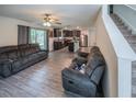 Open-concept living room featuring modern grey sofas, laminate floors, and seamless access to the kitchen at 938 Mansfield Rd, Tavares, FL 32778