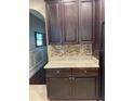 This butler's pantry features dark wood cabinets, granite countertops, and a tiled backsplash at 1446 Vivaldi Pl, Longwood, FL 32779