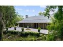 Beautiful home exterior featuring a stone patio, fountain, manicured greenery, and a durable metal roof at 13450 E Lake Mary Jane Rd, Orlando, FL 32832