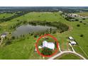 An aerial view of the property and surrounding area featuring a pond, green fields, and other houses at 1040 Timbers Dr, Fort Meade, FL 33841