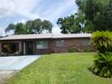 Inviting brick home with a lush green lawn, mature landscaping, and a spacious driveway at 112 Bishop St, Auburndale, FL 33823