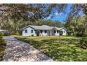 Light blue single-story home with a long driveway and mature landscaping at 1131 Country Oaks Blvd, Lake Wales, FL 33898
