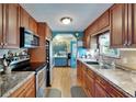Functional kitchen with stainless steel appliances, wood cabinets, and a view into the adjacent dining area at 1575 Longbow Dr, Lakeland, FL 33810