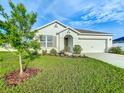 Single-story home with a well-manicured lawn, garden bed, and neutral-colored exterior at 1835 Jackson Oaks Dr, Bartow, FL 33830