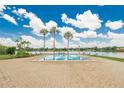 Inviting community pool surrounded by lounge chairs, palm trees, and a serene lake backdrop at 1920 E Edgewood Dr # D7, Lakeland, FL 33803