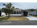 Charming single-story home featuring a covered carport, a palm tree, and a screened front porch at 2055 S Floral Ave # 45, Bartow, FL 33830