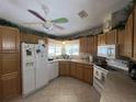 Functional kitchen featuring oak cabinets, white appliances, and a window over the sink offering great lighting at 2055 S Floral Ave # 45, Bartow, FL 33830