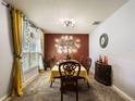 Traditional dining room with a decorative table, accent wall, and natural light from the window at 3334 Fawnwood Dr, Ocoee, FL 34761