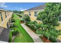 Townhome backyard featuring a green lawn, mature trees, and a walkway, with a pond beyond at 519 Sandstone St, Lakeland, FL 33809