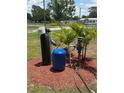 Water softener system with multiple tanks installed outdoors in a mulch bed surrounded by palm trees at 5217 Turtle Dove Trl, Lakeland, FL 33810