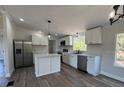 Modern kitchen featuring white cabinets, stainless steel appliances, an island, and luxury vinyl flooring at 7005 Dove Meadow Trl, Lakeland, FL 33810