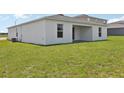Home showcasing a simple, covered patio area and a spacious, green backyard perfect for outdoor activities at 3528 Dahlia Dr, Haines City, FL 33844